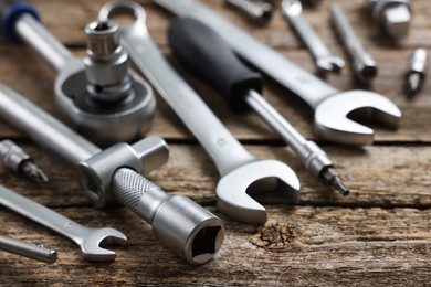 Photo of Different auto mechanic's tools on wooden table, closeup