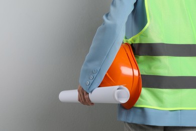 Engineer with hard hat and draft on grey background, closeup. Space for text