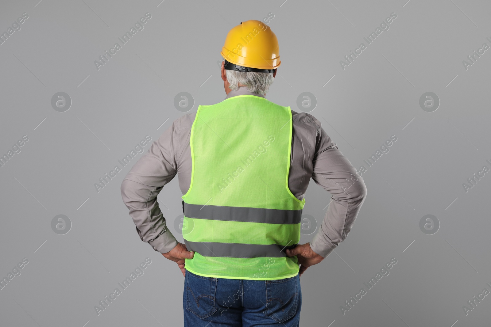 Photo of Engineer in hard hat on grey background, back view. Space for text