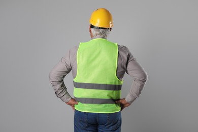 Engineer in hard hat on grey background, back view. Space for text