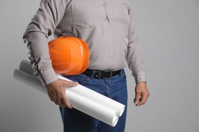 Engineer with hard hat and drafts on grey background, closeup. Space for text