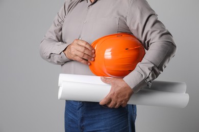 Photo of Engineer with hard hat and drafts on grey background, closeup