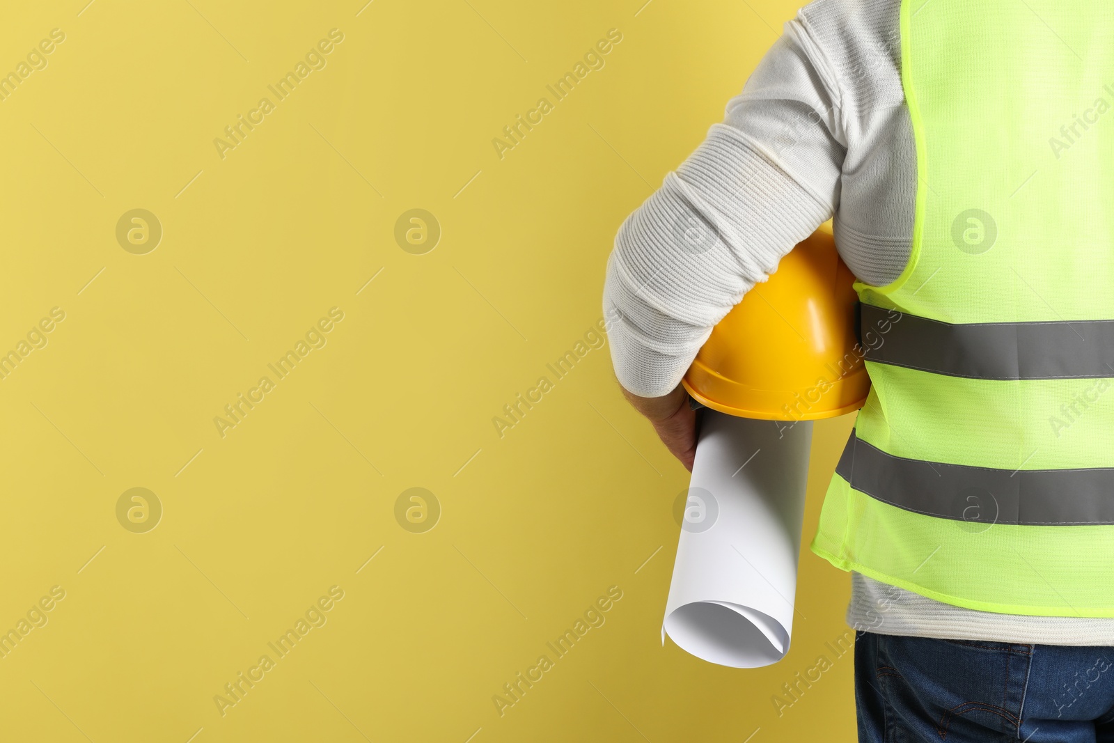 Photo of Engineer with hard hat and draft on yellow background, closeup. Space for text