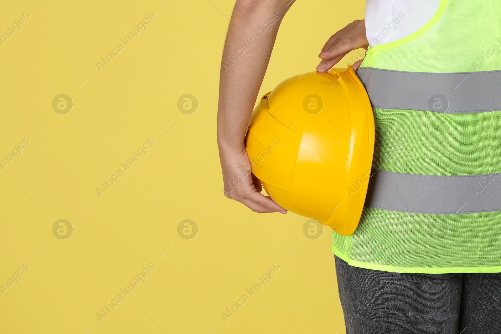 Photo of Engineer with hard hat on yellow background, closeup. Space for text