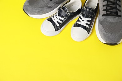 Photo of Big and small shoes on yellow background, above view. Space for text