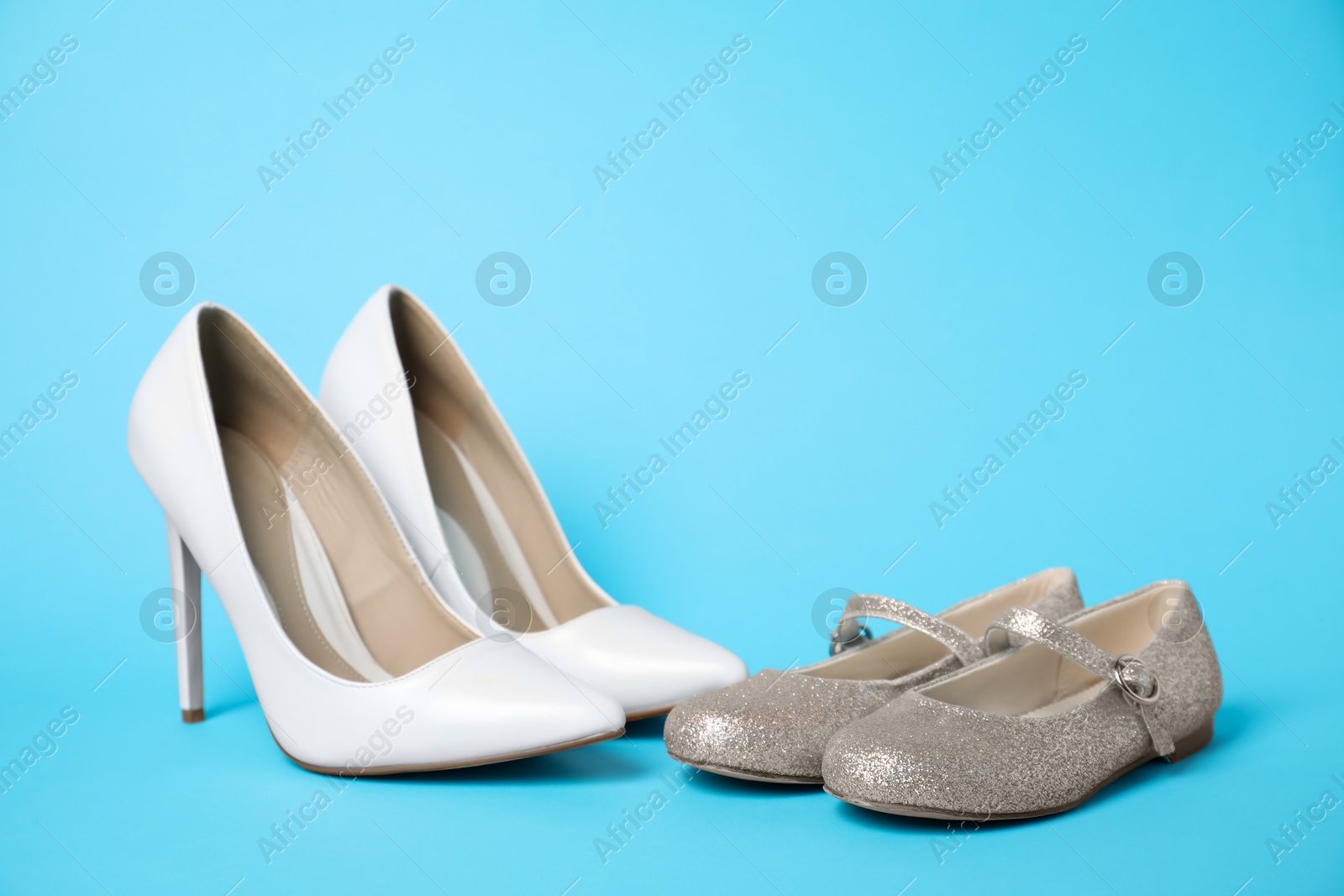 Photo of Big and small shoes on light blue background