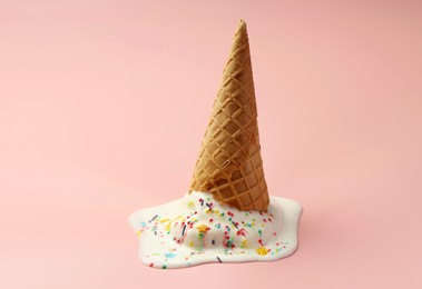 Photo of Melted ice cream in wafer cone on light pink background