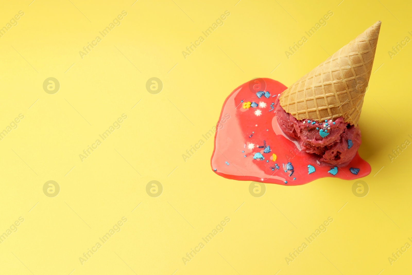 Photo of Melted ice cream in wafer cone on yellow background. Space for text