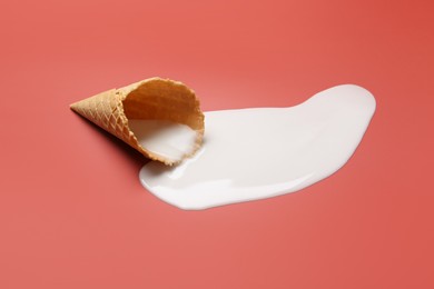 Melted ice cream and wafer cone on pale pink background