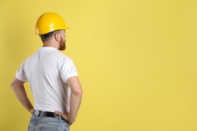 Photo of Engineer in hard hat on yellow background, space for text