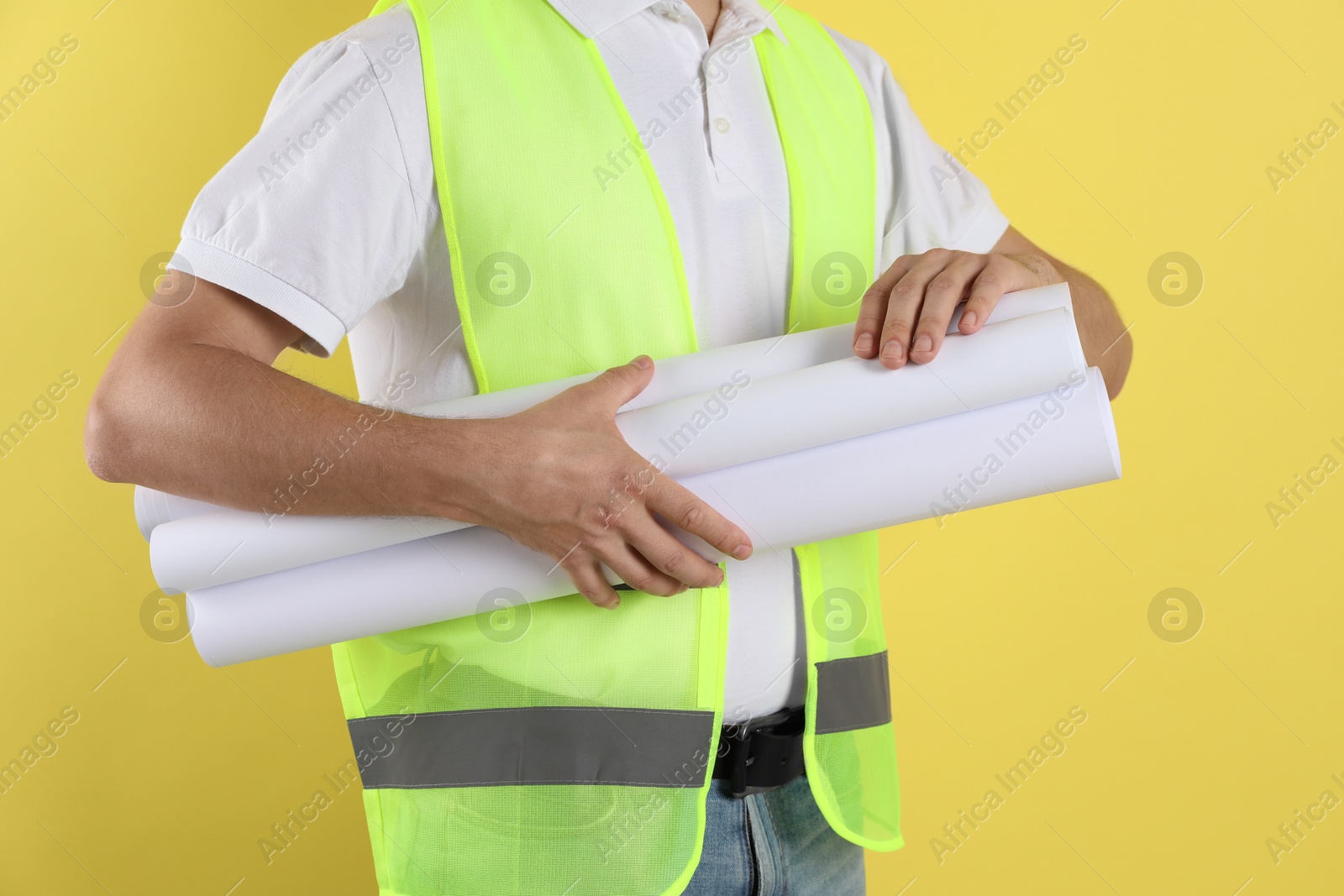 Photo of Engineer with drafts on yellow background, closeup