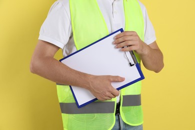 Photo of Engineer with clipboard on yellow background, closeup