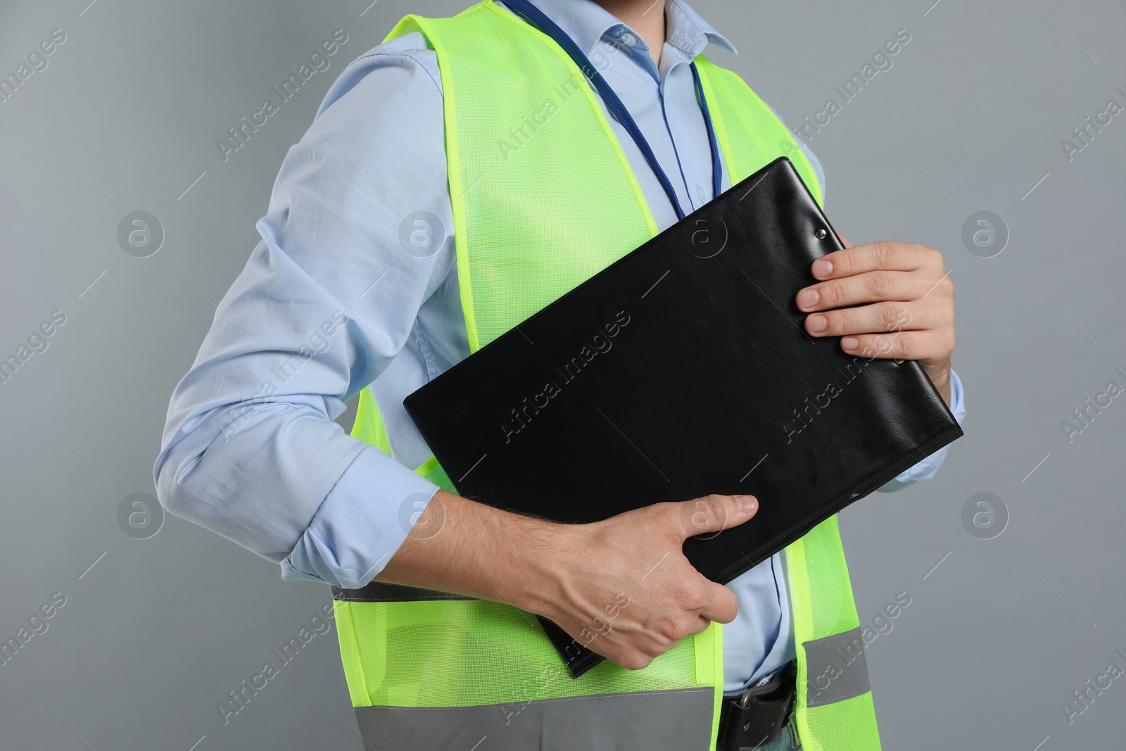 Photo of Engineer with clipboard on grey background, closeup