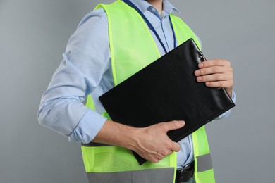 Engineer with clipboard on grey background, closeup