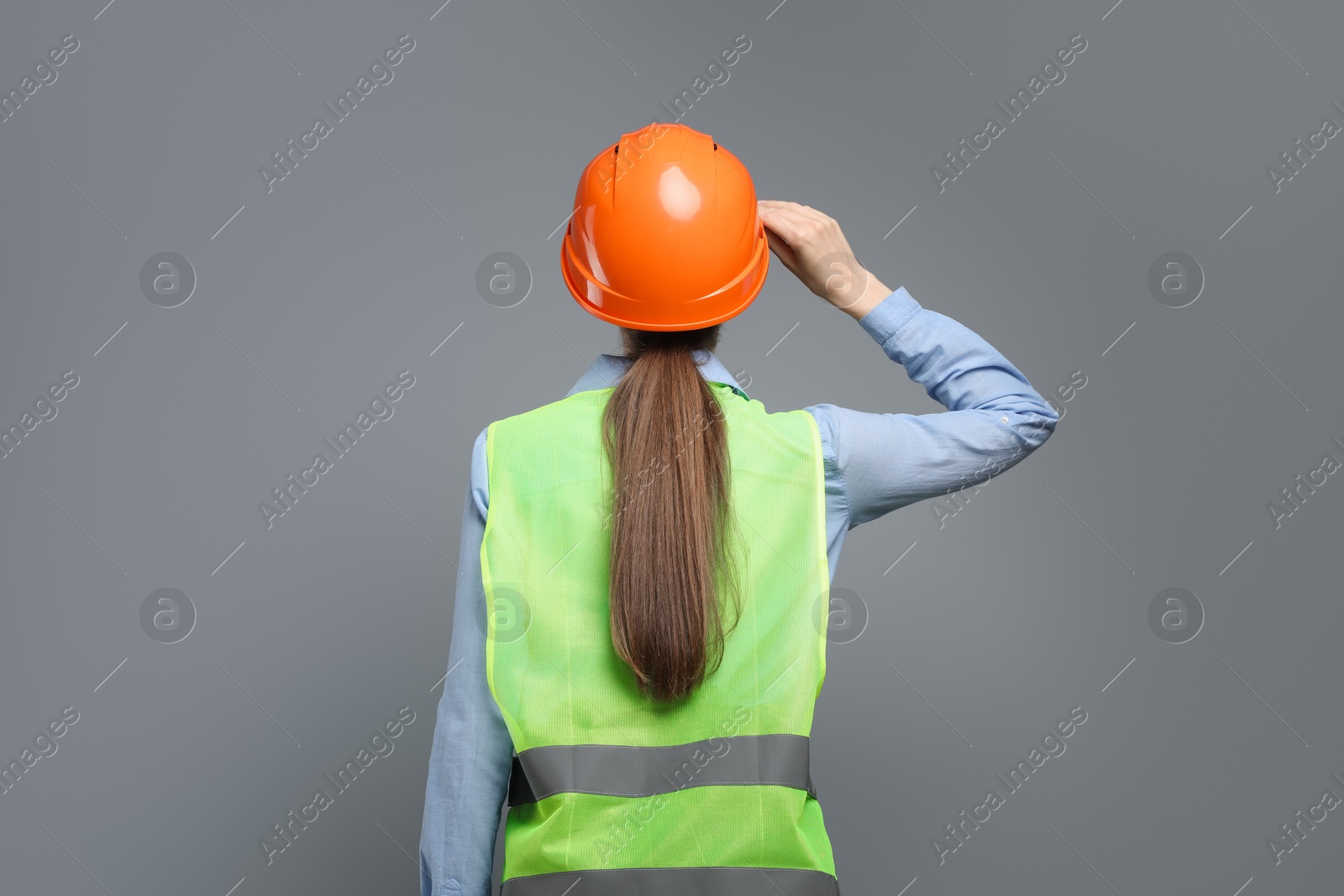 Photo of Engineer in hard hat on grey background, back view