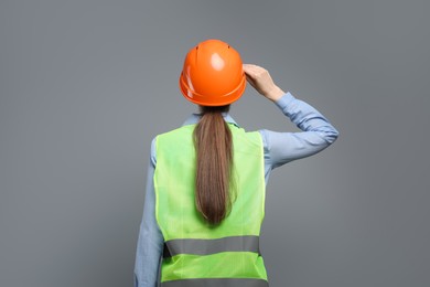 Engineer in hard hat on grey background, back view