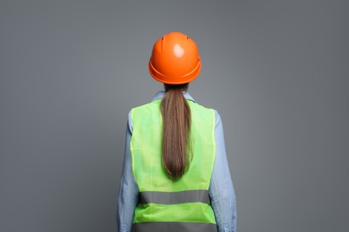 Photo of Engineer in hard hat on grey background, back view