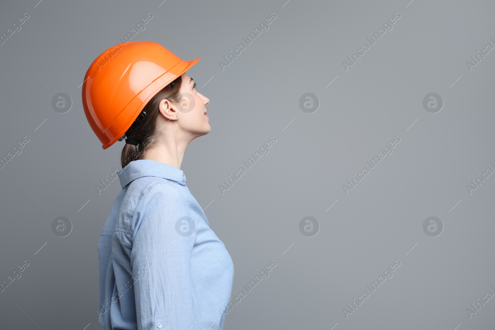 Photo of Engineer in hard hat on grey background, space for text