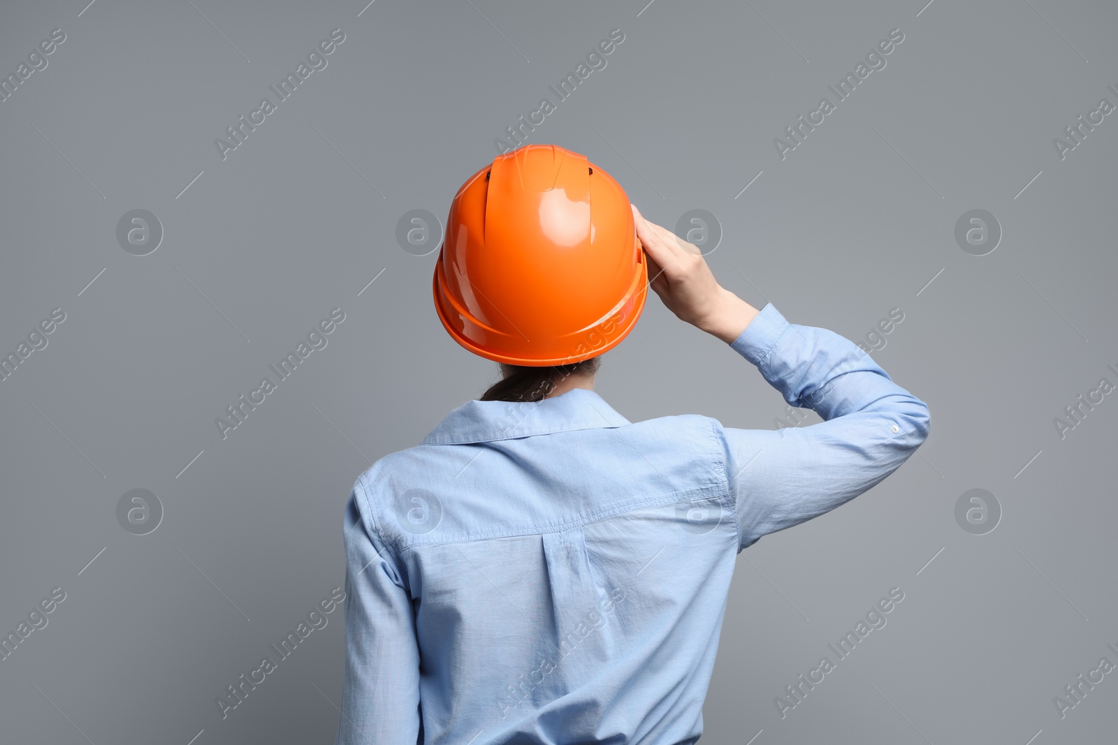 Photo of Engineer in hard hat on grey background, back view