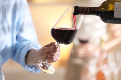 Photo of Pouring red wine into woman`s glass, selective focus