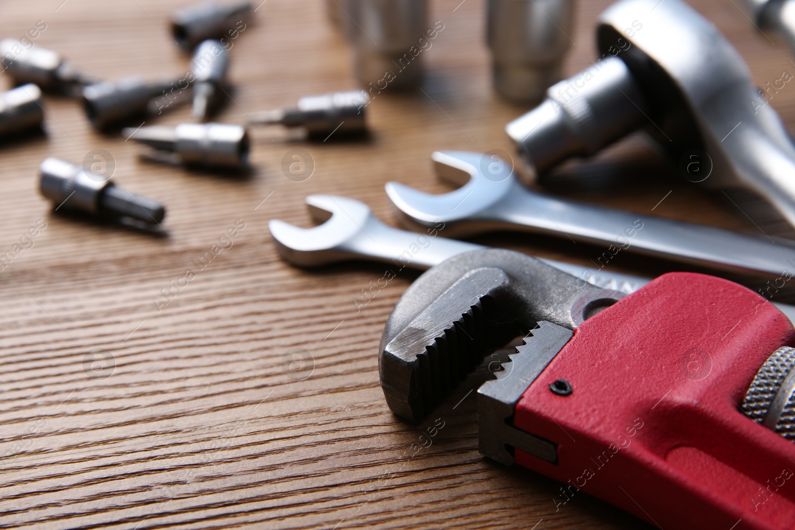 Photo of Different auto mechanic's tools on wooden table, closeup