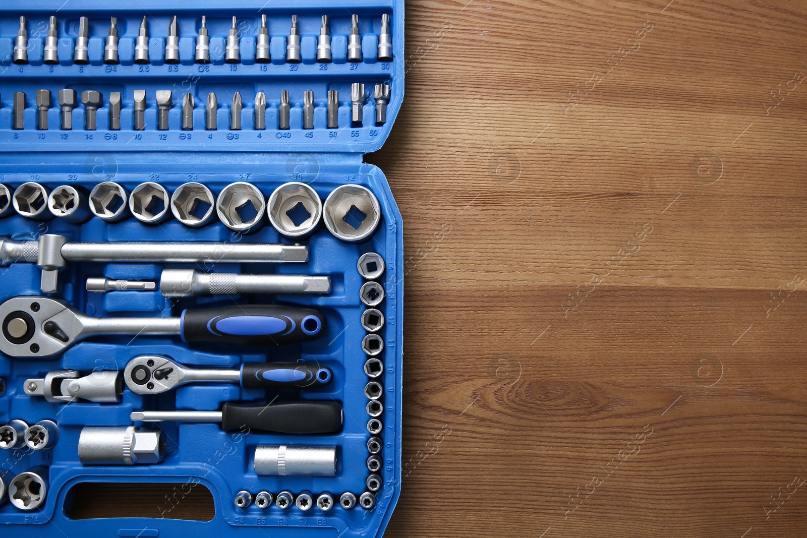 Photo of Auto mechanic's tools in plastic box on wooden table, top view. Space for text