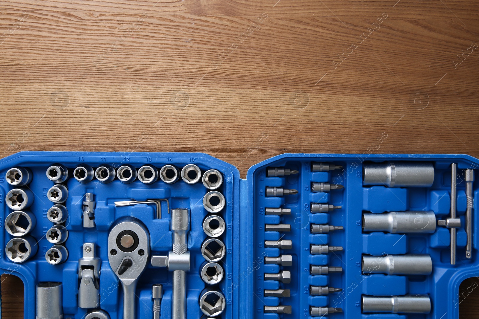 Photo of Auto mechanic's tools in plastic box on wooden table, top view. Space for text