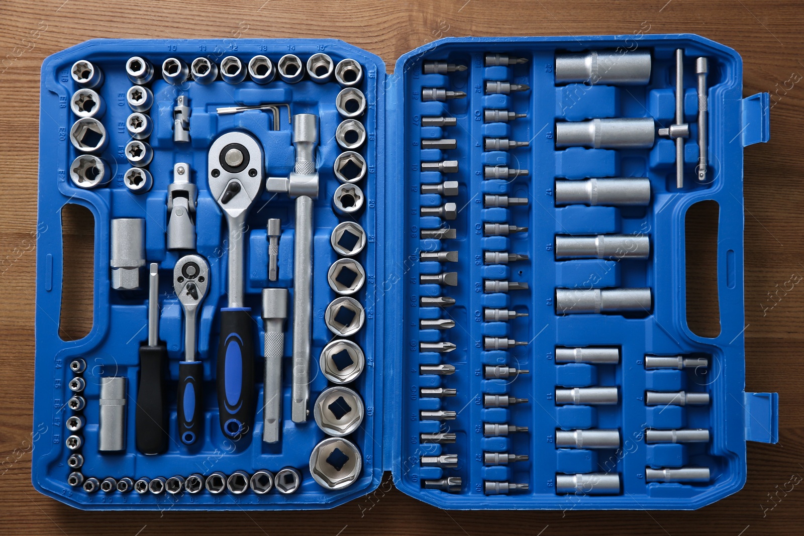 Photo of Auto mechanic's tools in plastic box on wooden table, top view