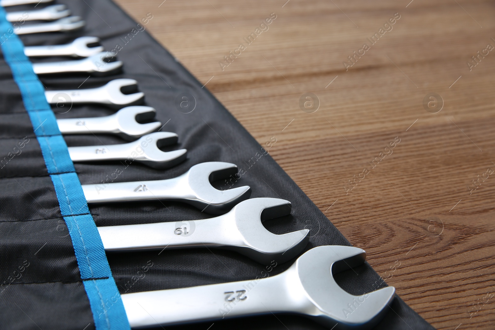 Photo of Auto mechanic's tools in case on wooden table, closeup. Space for text