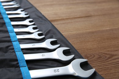 Photo of Auto mechanic's tools in case on wooden table, closeup. Space for text