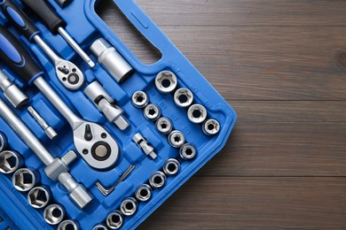 Photo of Auto mechanic's tools in plastic box on wooden table, top view. Space for text