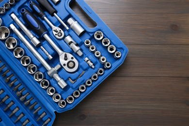 Photo of Auto mechanic's tools in plastic box on wooden table, top view. Space for text