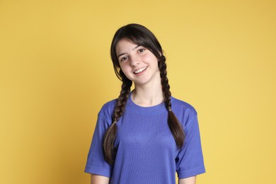 Portrait of smiling teenage girl on yellow background