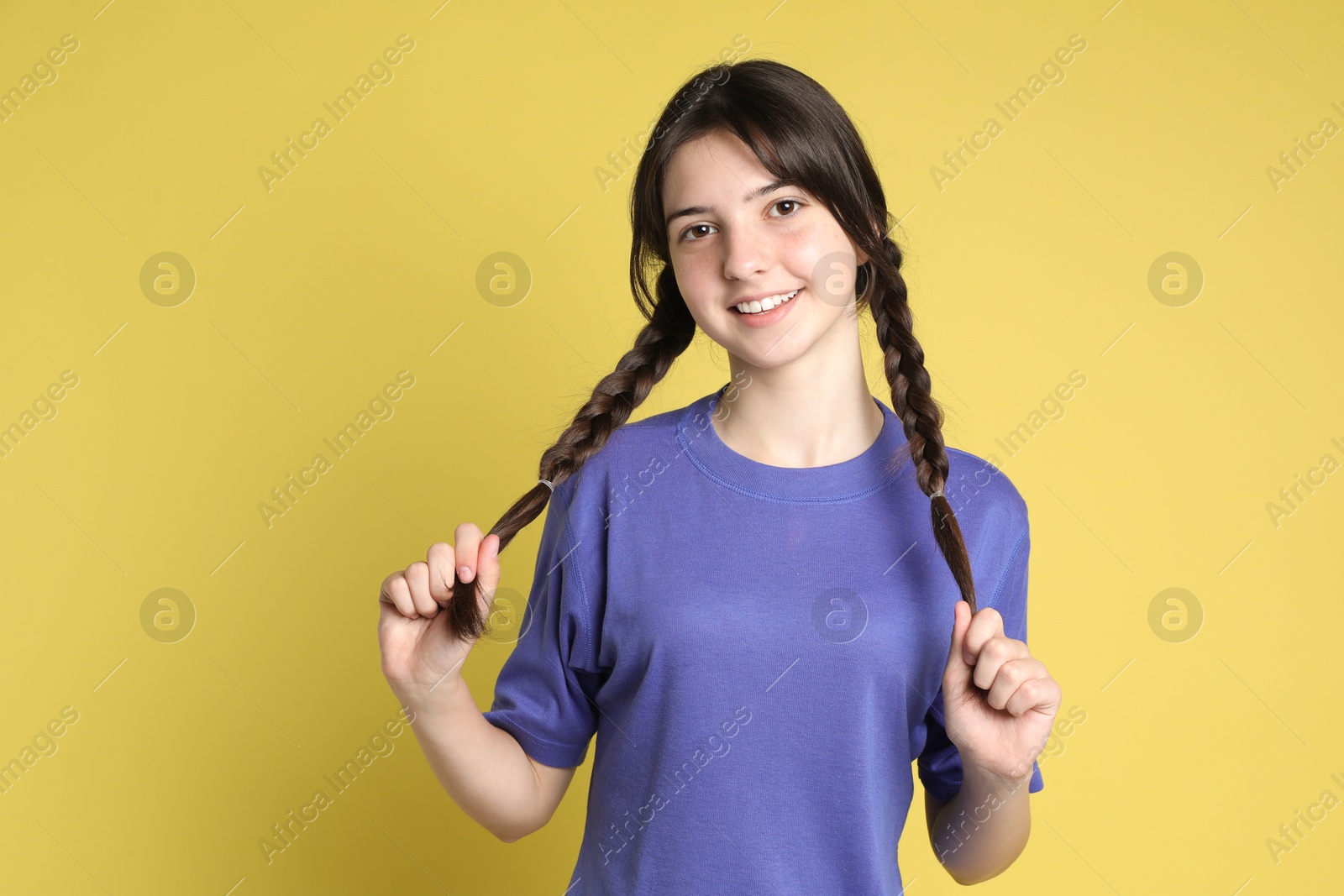 Photo of Portrait of smiling teenage girl on yellow background