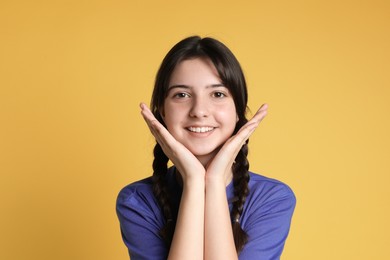 Portrait of smiling teenage girl on yellow background