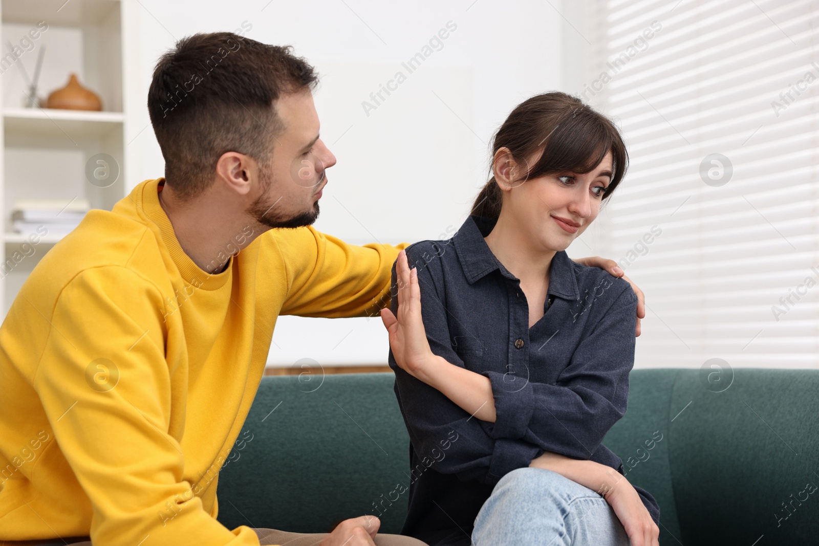 Photo of Embarrassed woman refusing from man's kiss at home