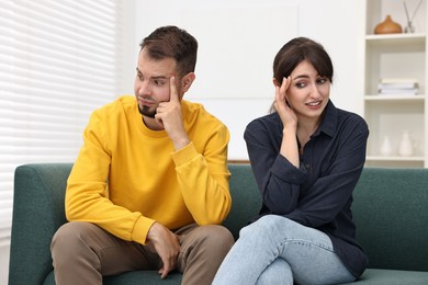 Photo of Embarrassed couple ignoring each other on sofa at home