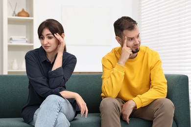 Embarrassed couple ignoring each other on sofa at home