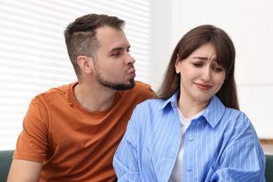 Photo of Man trying to kiss embarrassed woman at home