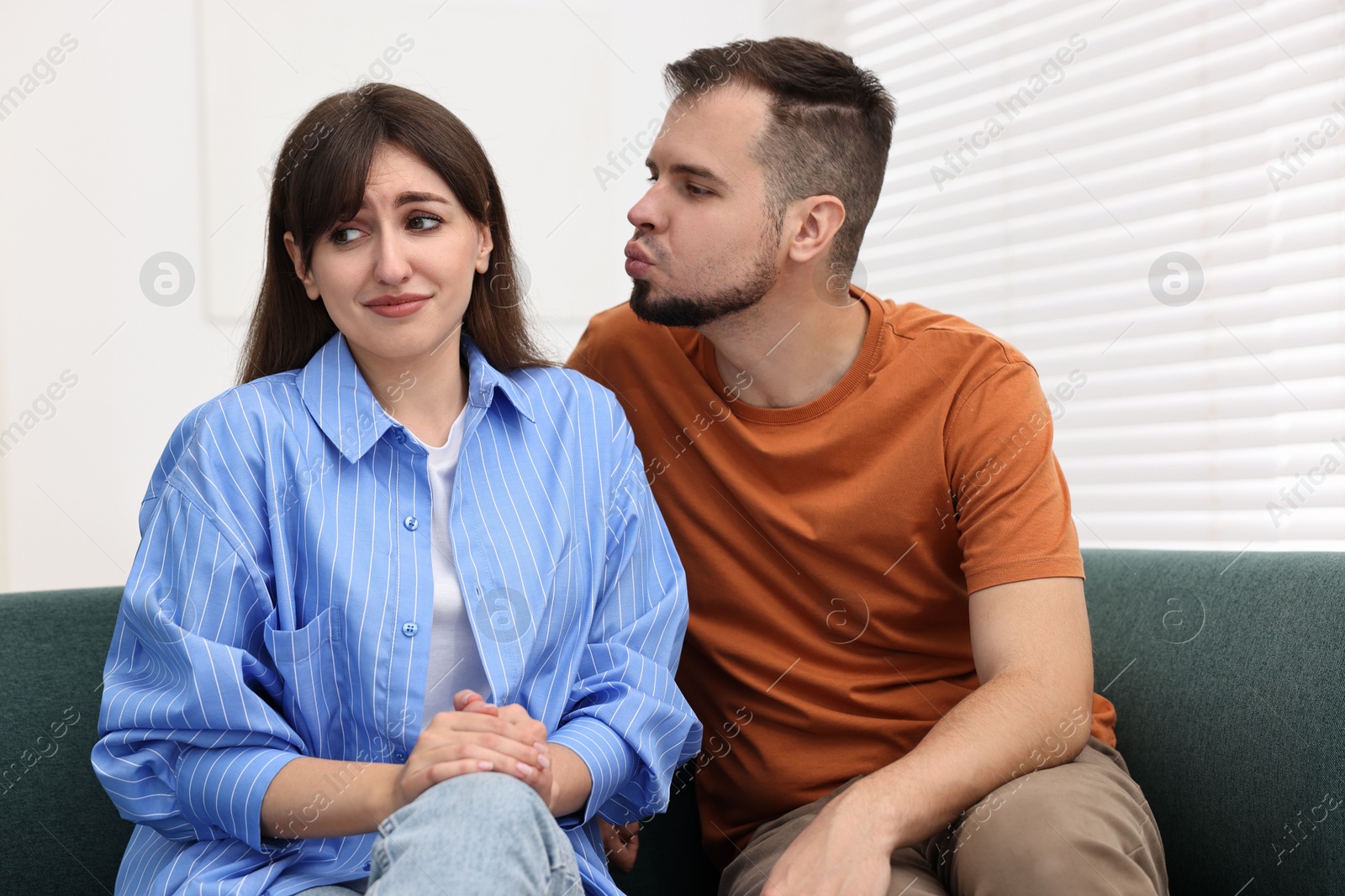 Photo of Man trying to kiss embarrassed woman at home