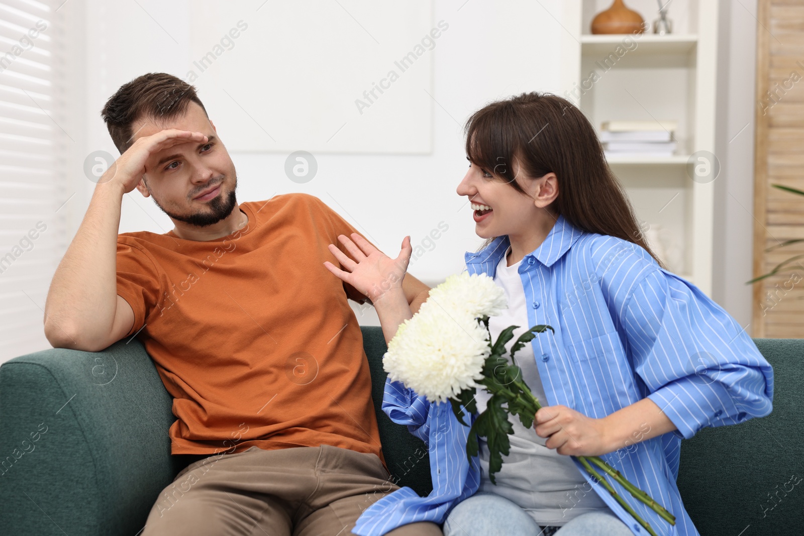 Photo of Obsessive woman with flowers flirting with embarrassed man at home