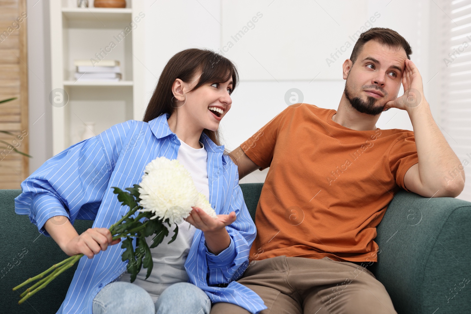 Photo of Obsessive woman with flowers flirting with embarrassed man at home