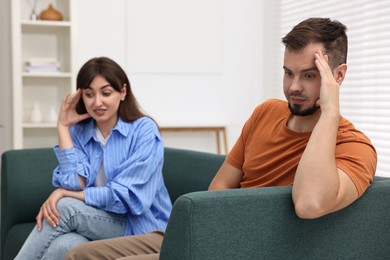 Photo of Embarrassed couple ignoring each other on sofa at home