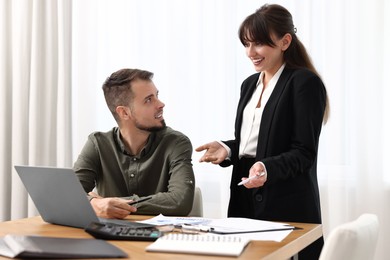 Photo of Smiling consultant working with client at table in office. Business meeting