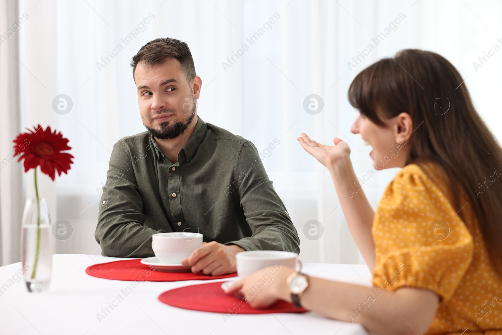 Photo of Bad date. Obsessive woman talking to embarrassed man at table indoors