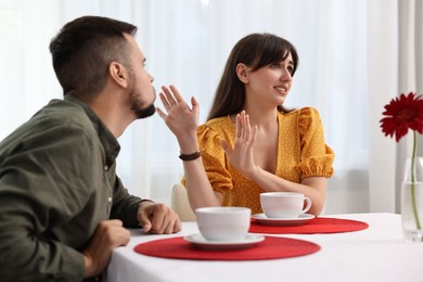 Bad date. Embarrassed woman refusing from man's kiss indoors