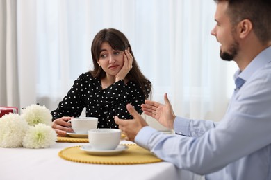 Photo of Embarrassing date. Obsessive man talking to bored woman at table indoors