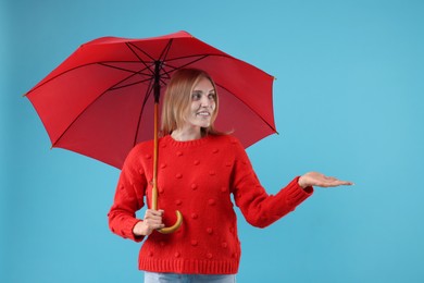 Woman with red umbrella on light blue background