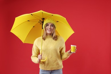 Photo of Woman with yellow umbrella and paper cup on red background, space for text