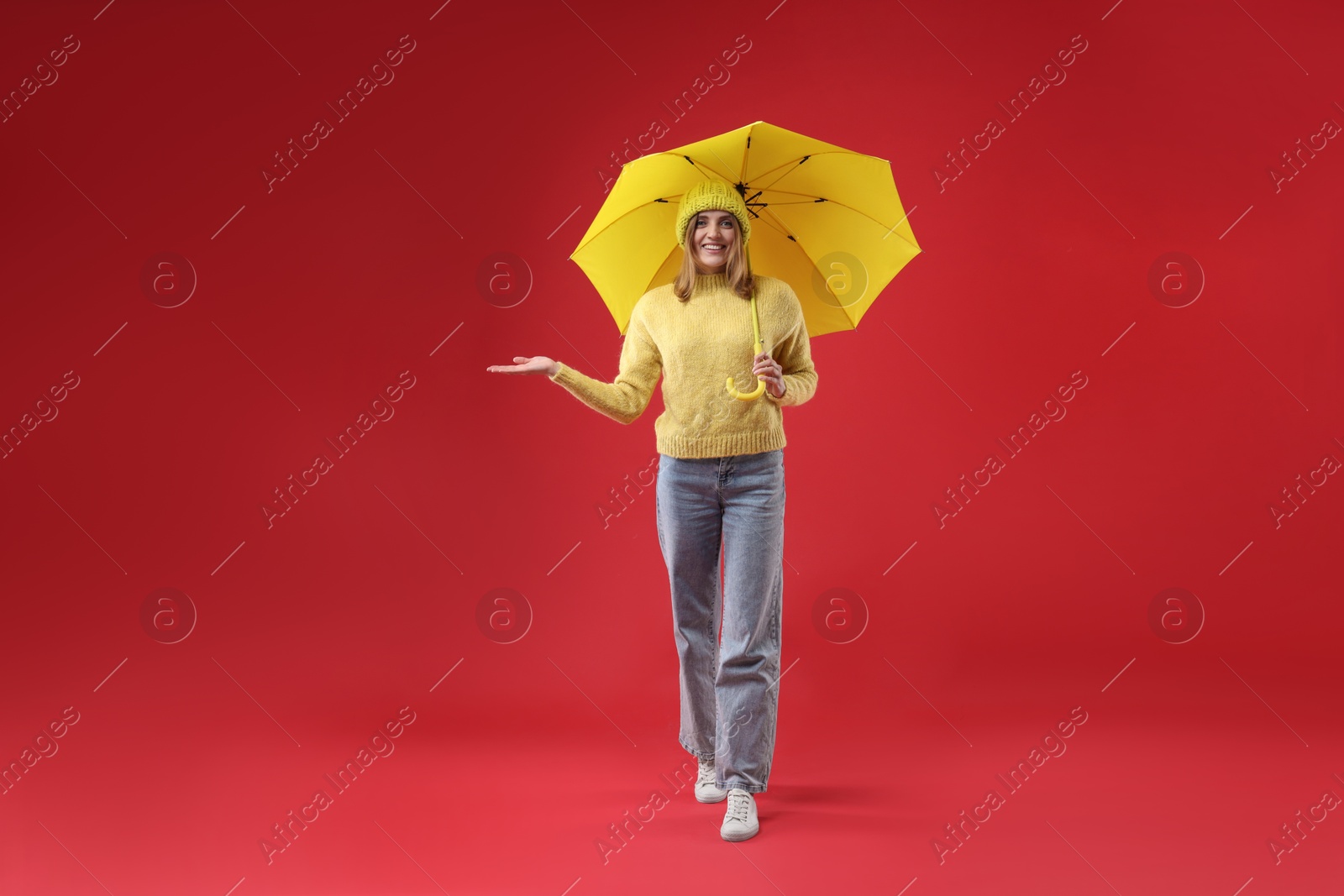 Photo of Woman with yellow umbrella on red background